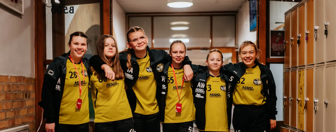 Ungdomslag står tillsammans i korridoren under en stor idrottsturnering. Perfekt för internationella lag och tävlingar.