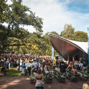 Publik vid en utomhuskonsert i Göteborgs grönområde en solig dag.
