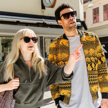 Två personer shoppar i Göteborgs innerstad, omgivna av trendiga butiker och kaféer på Magasinsgatan.